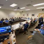 Man giving a speech to a group of people in a conference room