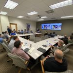Man giving a speech to a group of people in a conference room