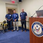 3 men standing besides speaker podium