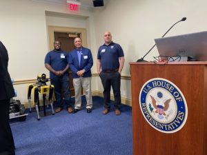 3 men standing besides speaker podium
